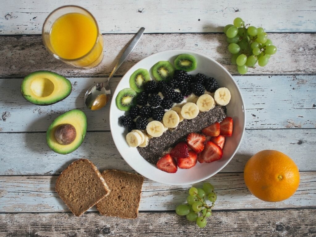 A healthy ceramic breakfast bowl of organic chia seeds layered with strawberries, blackberries, kiwi, bananas, and fresh fruits on a rustic wooden table